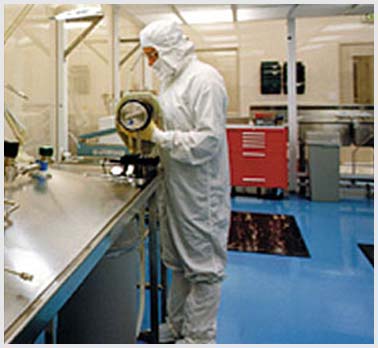 Worker in bunny suit at a workbench.