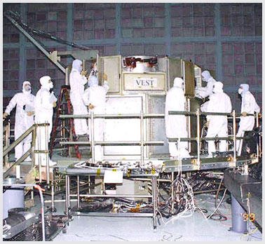 Photo of many workers in a small space surrounding a payload.