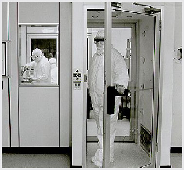 Photo of a fully suited worker exiting an air shower and entering a cleanroom.